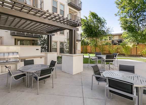 A patio with a table and chairs under a pergola. at Cirrus Redwood City Apartments, Redwood City, CA, 94061