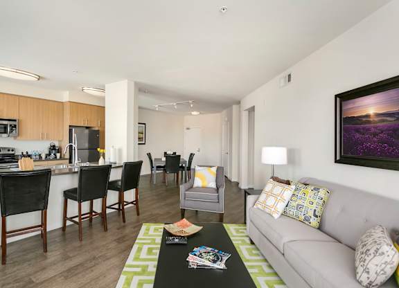 A modern living room with a grey couch and a green rug. at Cirrus Redwood City Apartments, Redwood City, CA, 94061