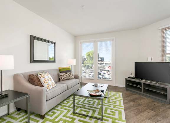 A living room with a grey couch, a coffee table, and a television. at Cirrus Redwood City Apartments, California, 94061