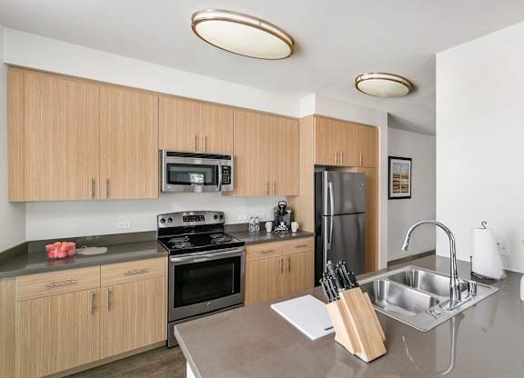 A kitchen with a stove, refrigerator, microwave, and sink. at Cirrus Redwood City Apartments, Redwood City, CA, 94061