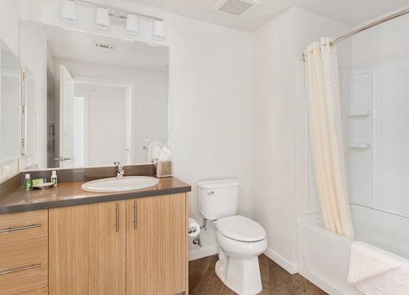 A white toilet sits next to a sink in a bathroom at Cirrus Redwood City Apartments, Redwood City, California