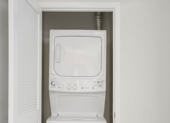 A white washing machine is in a white door. at Cirrus Redwood City Apartments, California, 94061
