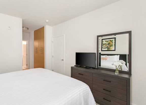 A bedroom with a bed, dresser, and mirror. at Cirrus Redwood City Apartments, Redwood City, California