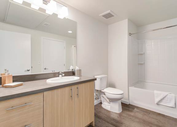 A white bathroom with a toilet, sink, and bathtub. at Cirrus Redwood City Apartments, California