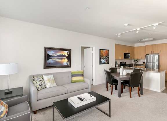 A living room with a grey couch, a coffee table, and a dining table with chairs. at Cirrus Redwood City Apartments, Redwood City, CA, 94061