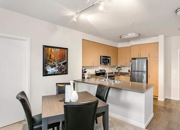 A kitchen with a table and chairs and a painting on the wall. at Cirrus Redwood City Apartments, Redwood City