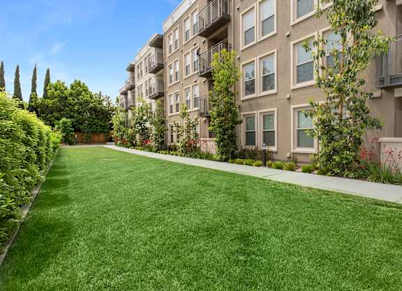 A long grass lawn in front of apartment buildings. at Cirrus Redwood City Apartments, Redwood City, CA, 94061