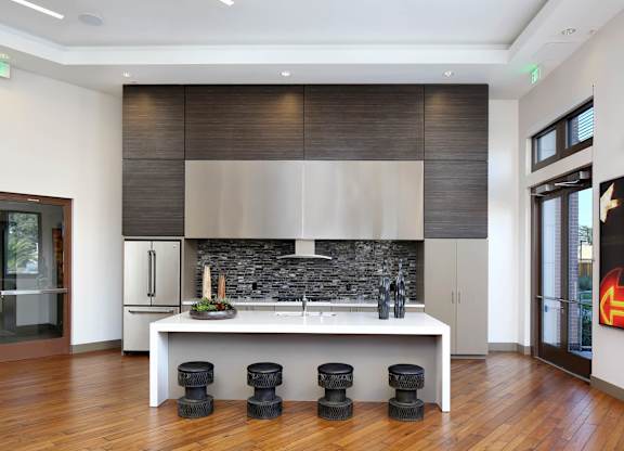 A modern kitchen with a white countertop and black stools. at Cirrus Redwood City Apartments, Redwood City
