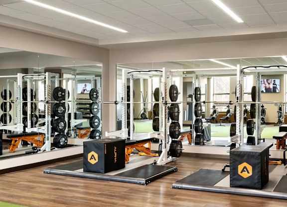 A gym with a variety of equipment including weightlifting machines and a television at One West,New York, NY.