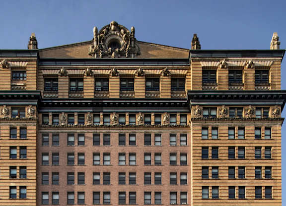 A large building with a statue on top of it. at One West,New York, NY