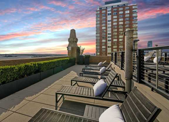A balcony with chairs and a building in the background at One West, New York, NY.