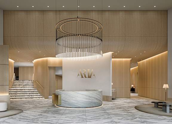 A luxurious lobby with a large circular chandelier and a reception desk with the letters "ARIA" on it.