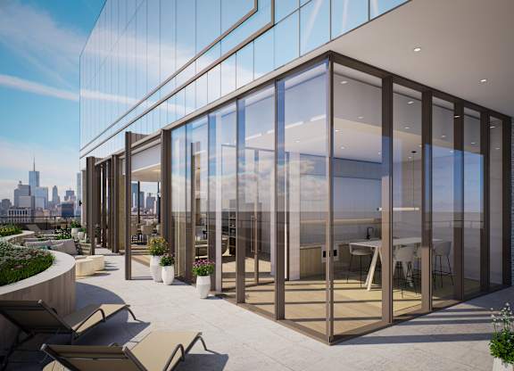 A modern building with glass walls and a terrace with chairs and plants.