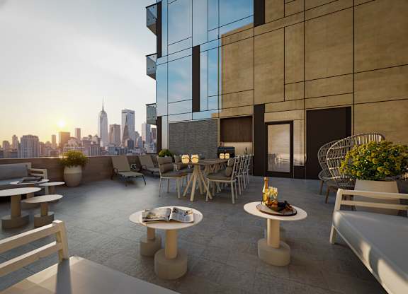 A modern outdoor seating area with a view of the city skyline at sunset.