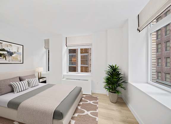 A bedroom with a bed, a potted plant, and a window with a view of a building at Aria, New York, New York
