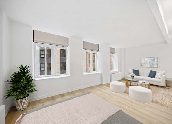 A living room with a white couch, a potted plant, and a rug at Aria, New York, 10038