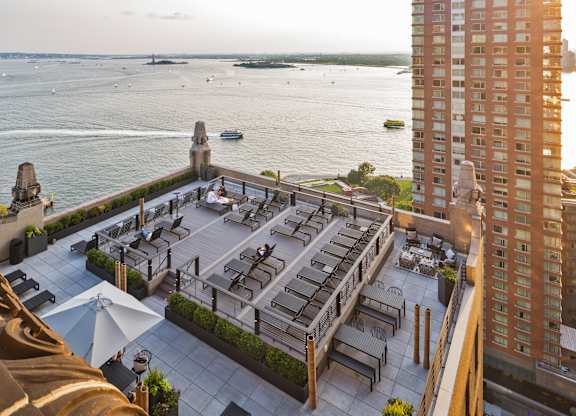 A rooftop patio with a view of the water and boats at One West,New York, NY.