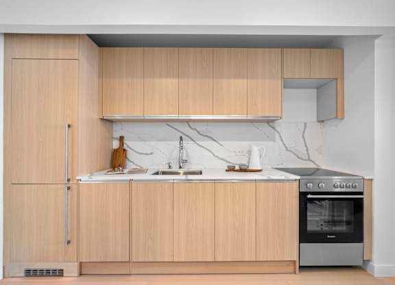 A kitchen with wooden cabinets and a white countertop at One West,New York, NY.