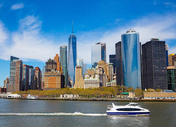 A boat is sailing in front of a city skyline at Aria, New York, NY