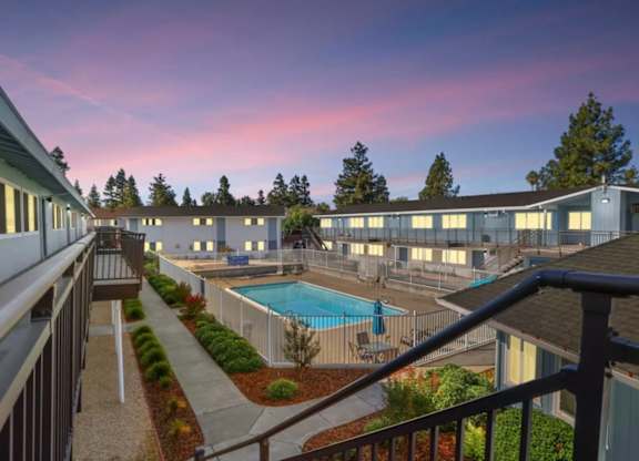A view of a pool and apartment complex from a balcony.