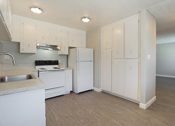 A kitchen with white cabinets and appliances.