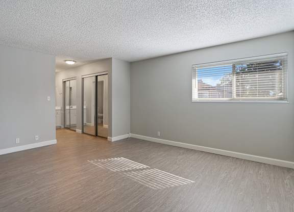 A room with a window and a wooden floor.