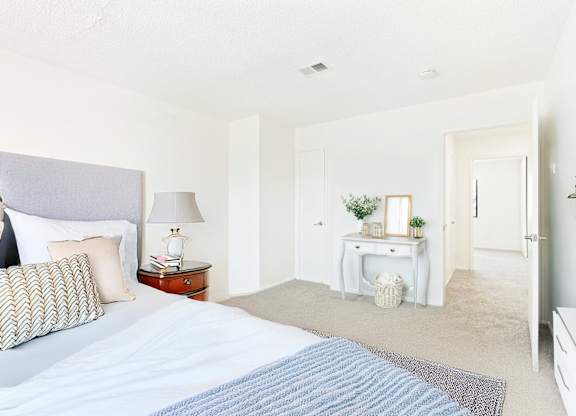 A bedroom with a large bed and a desk with a lamp.