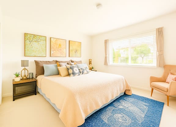 A bedroom with a bed, chair, and pictures on the wall.
