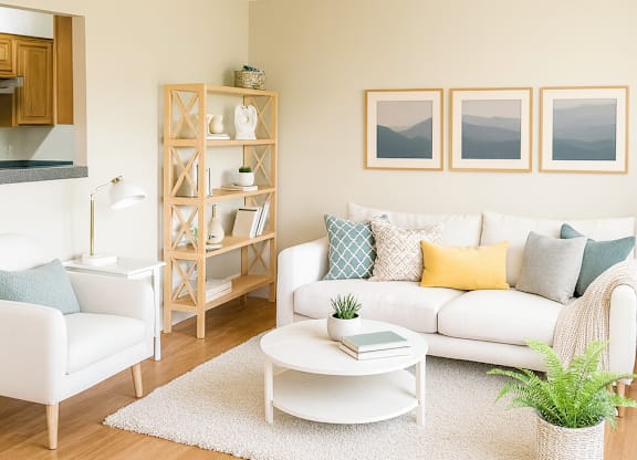A living room with a white couch, a white chair, a white coffee table, a white rug, a white shelf, and three pictures on the wall.