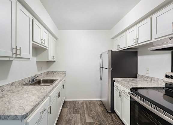 A kitchen with white cabinets and a marble countertop.