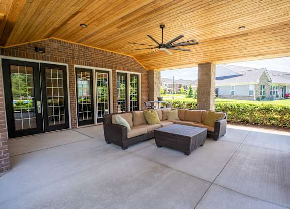A patio with a couch and a ceiling fan.