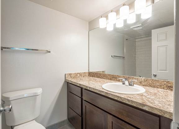 A bathroom with a toilet, sink, and mirror.