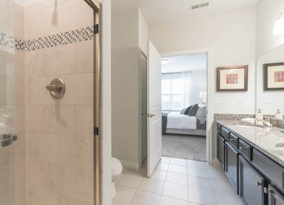 a bathroom with a shower and a sink and a bedroom