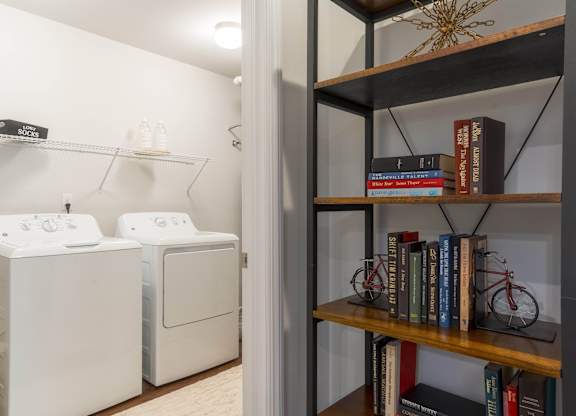 a laundry room with a washer and dryer and a book shelf with books