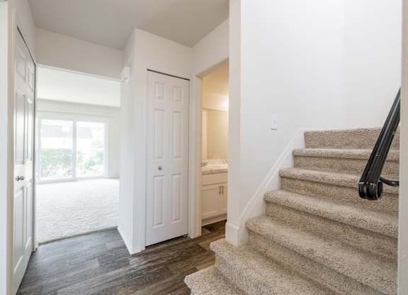 A staircase with a beige carpeted runner and a black metal handrail.