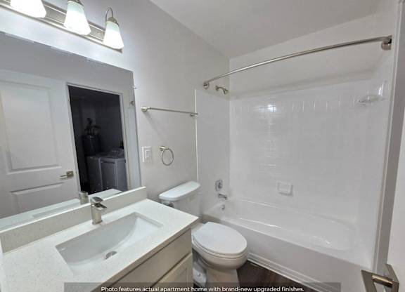 A white bathroom with a sink, toilet, and shower.