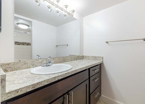 A bathroom with a sink, mirror, and a towel bar.