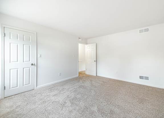 A room with a carpeted floor and a white door.