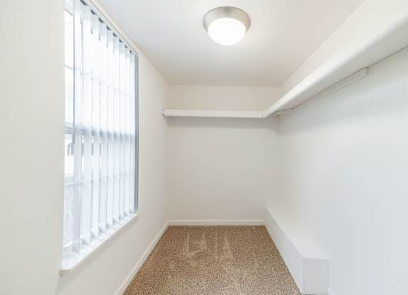 A room with a carpeted floor and a window with blinds.