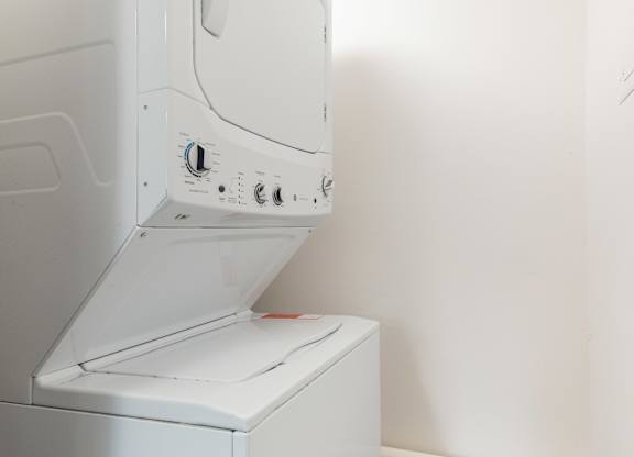 A white dryer is sitting in a room with a white wall.