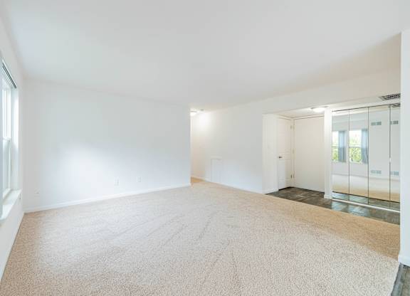 A large empty room with a carpeted floor and white walls.