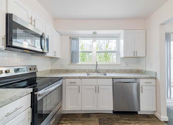 A kitchen with white cabinets and a black stove top oven.