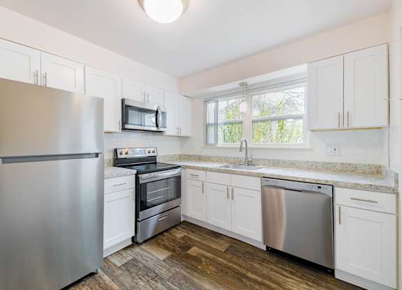A kitchen with a stainless steel refrigerator, microwave, oven, and dishwasher.