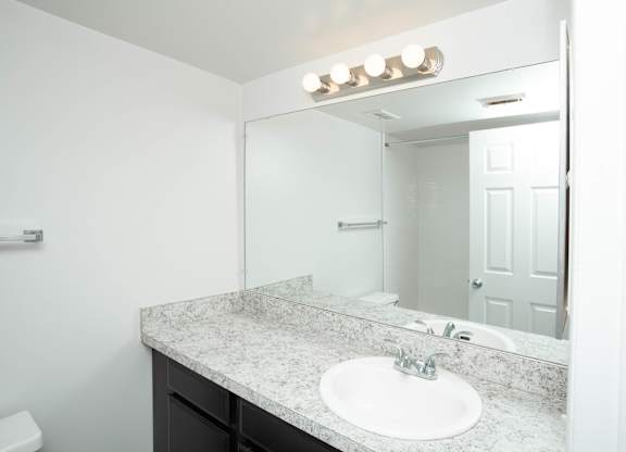A bathroom with a sink, mirror, and lights.