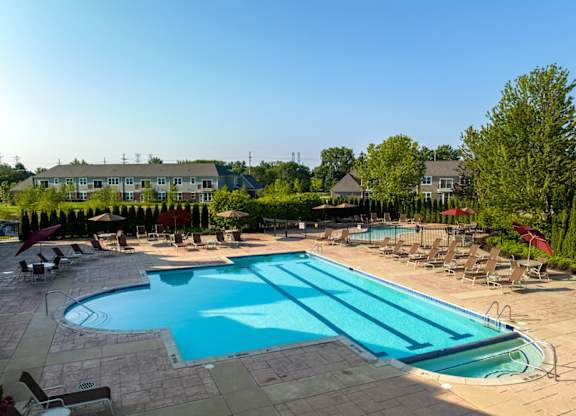 A large swimming pool surrounded by lounge chairs and trees.