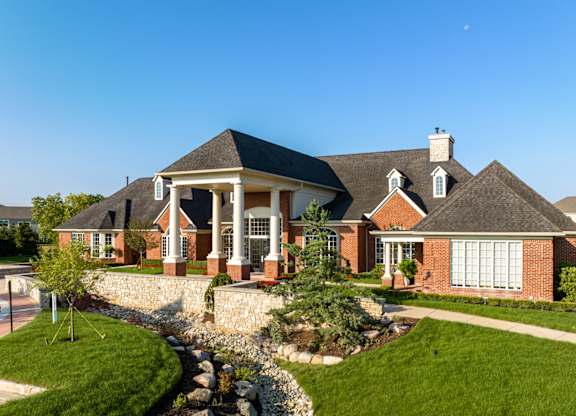 a large brick house with a front porch and a landscaped yard