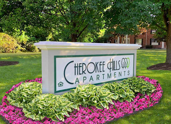A sign for Cherokee Hills Apartments is surrounded by flowers.