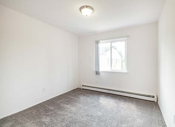 A room with a window and a radiator on the wall.