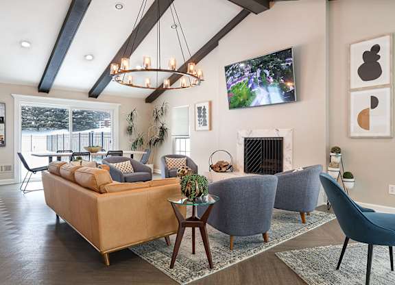 A living room with a large couch, a fireplace, and a TV mounted on the wall.