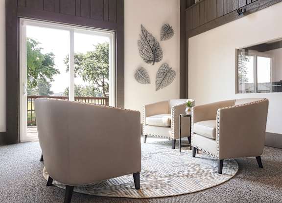 A living room with a large chair and a smaller chair with a table in between.